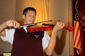 Junior Corey Koss plays the first song, "Amazing Grace", on the new violin donated by Mr. John Zelt '63.